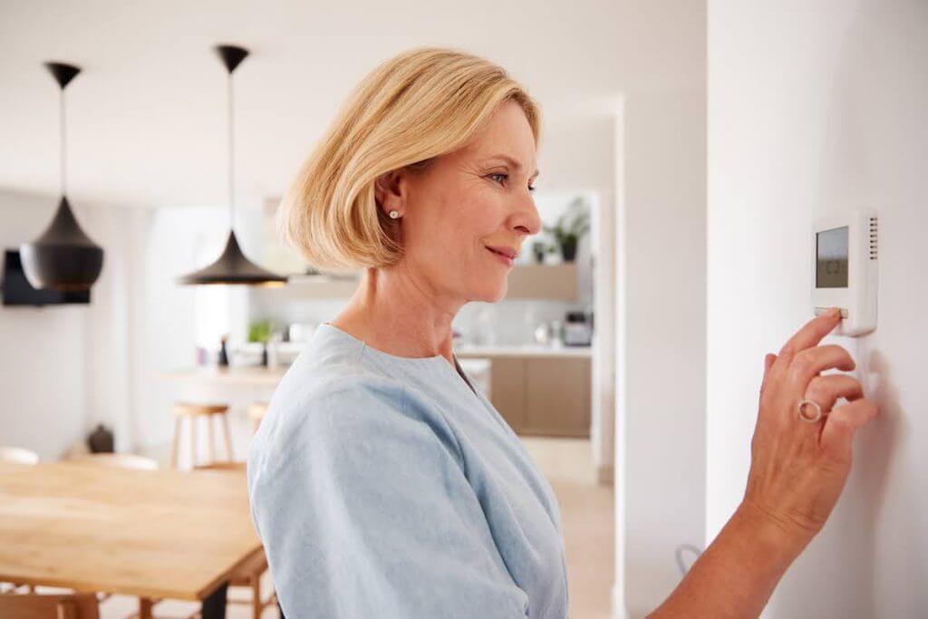 woman adjusting heating on wall